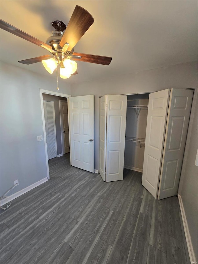 unfurnished bedroom featuring baseboards, dark wood-style flooring, a closet, and ceiling fan