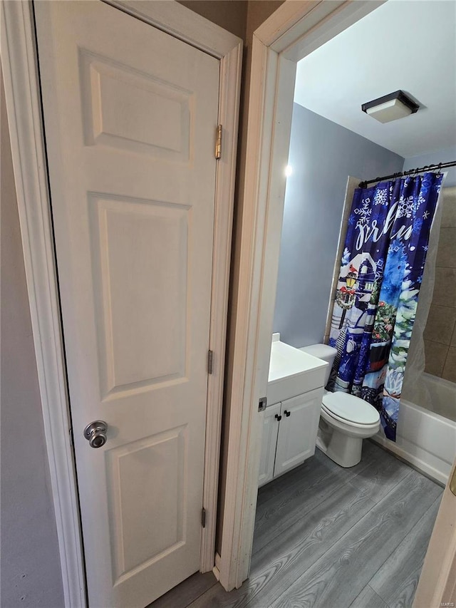 bathroom featuring vanity, toilet, wood finished floors, and shower / bath combo with shower curtain