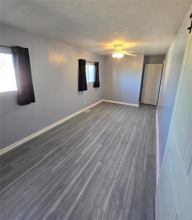 unfurnished room with ceiling fan, baseboards, a textured ceiling, and wood finished floors