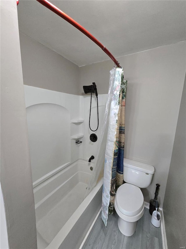 full bathroom with baseboards, toilet, wood finished floors, and shower / tub combo