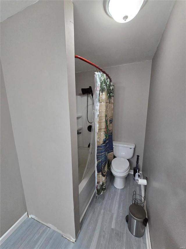 full bath with baseboards, toilet, wood finished floors, and shower / tub combo with curtain