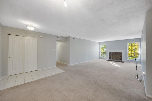 unfurnished living room featuring a textured ceiling, light carpet, and a brick fireplace