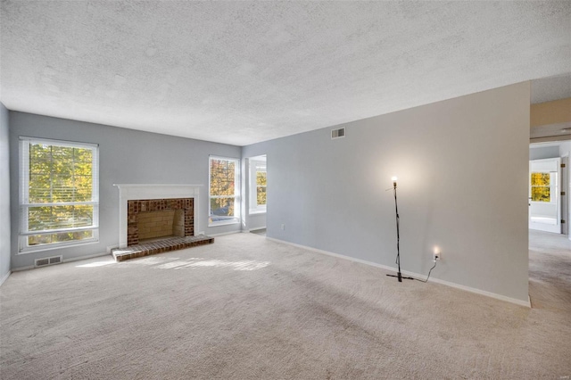 unfurnished living room featuring a textured ceiling, a fireplace, a wealth of natural light, and light carpet