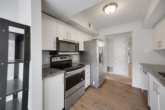 kitchen with white cabinetry, a textured ceiling, and appliances with stainless steel finishes