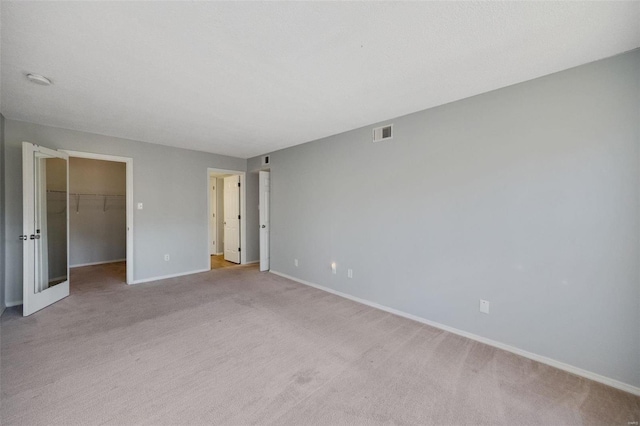 unfurnished bedroom featuring light carpet, a walk in closet, and a closet