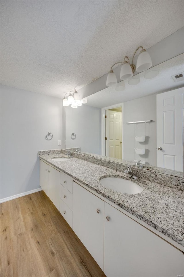 bathroom with a textured ceiling, vanity, and hardwood / wood-style flooring