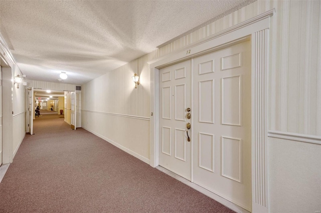 corridor with carpet and a textured ceiling