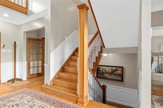 staircase featuring hardwood / wood-style flooring, ornate columns, and ornamental molding