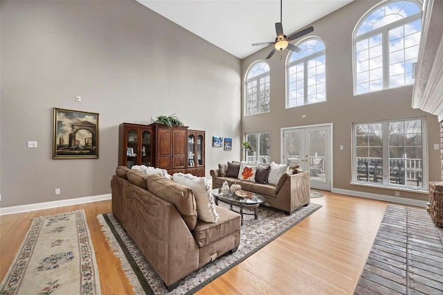 living room featuring plenty of natural light, light wood-type flooring, and a high ceiling