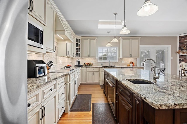 kitchen featuring a kitchen island with sink, sink, appliances with stainless steel finishes, light hardwood / wood-style floors, and dark brown cabinetry