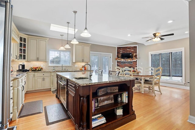 kitchen featuring cream cabinets, decorative light fixtures, a center island with sink, and sink