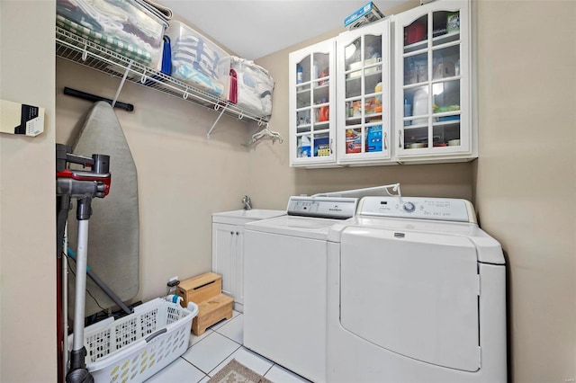 clothes washing area with washer and clothes dryer, light tile patterned flooring, cabinets, and sink