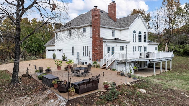 rear view of house with french doors, a patio, a garage, and a deck