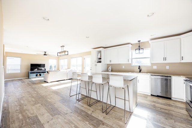 kitchen with stainless steel appliances, a sink, white cabinetry, and a center island