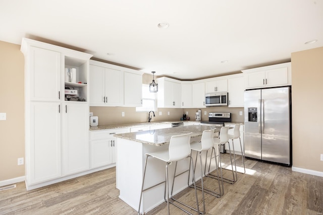 kitchen with open shelves, white cabinetry, stainless steel appliances, and a center island