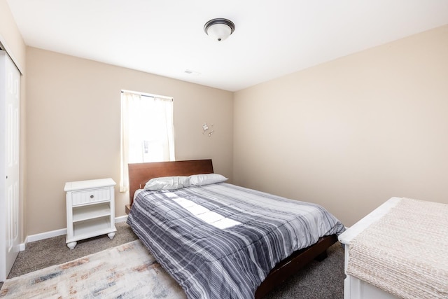 bedroom with a closet, light colored carpet, and baseboards