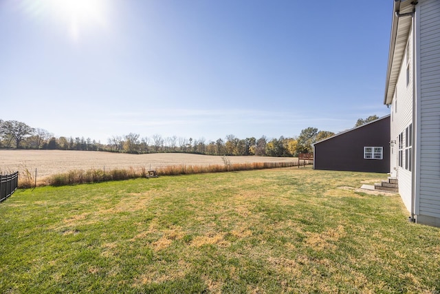 view of yard featuring entry steps, fence, and a rural view