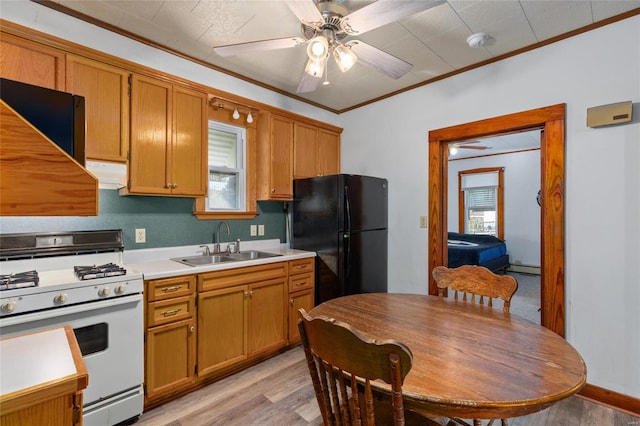 kitchen featuring black refrigerator, light hardwood / wood-style flooring, white gas stove, ornamental molding, and sink