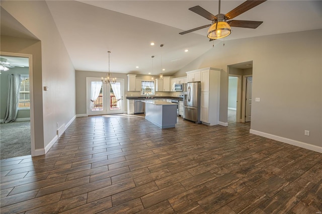 kitchen with dark wood-type flooring, stainless steel appliances, a center island, and decorative light fixtures