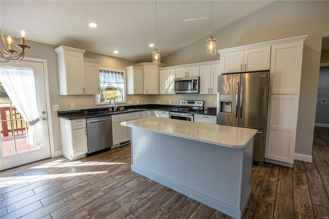 kitchen featuring dark hardwood / wood-style floors, stainless steel appliances, vaulted ceiling, and decorative light fixtures