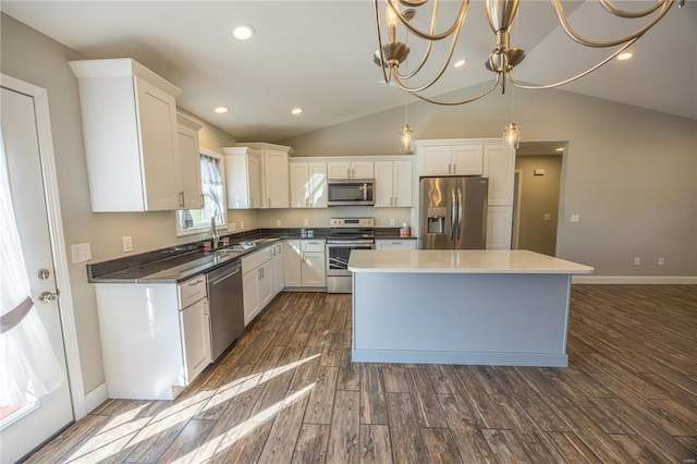 kitchen with lofted ceiling, white cabinets, stainless steel appliances, and dark hardwood / wood-style floors