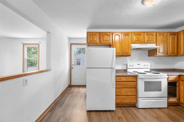 kitchen with a textured ceiling, white appliances, and light hardwood / wood-style floors