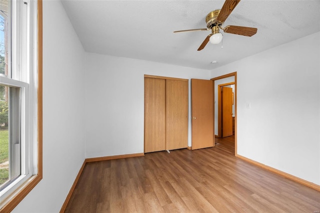 unfurnished bedroom with a closet, multiple windows, ceiling fan, and light hardwood / wood-style flooring