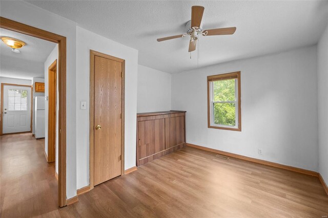 spare room with a textured ceiling, light hardwood / wood-style floors, and ceiling fan