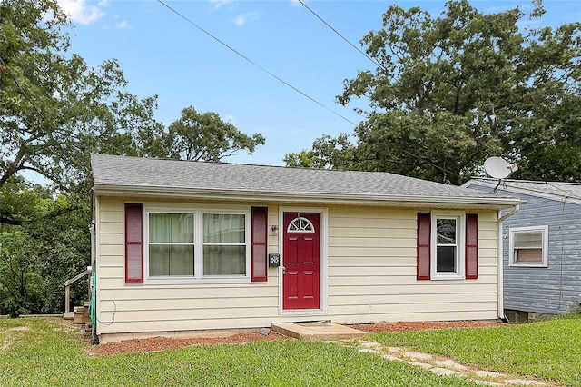 view of front of property featuring roof with shingles and a front lawn