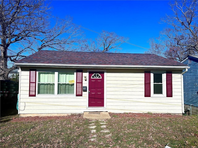 view of front of house with roof with shingles and a front yard