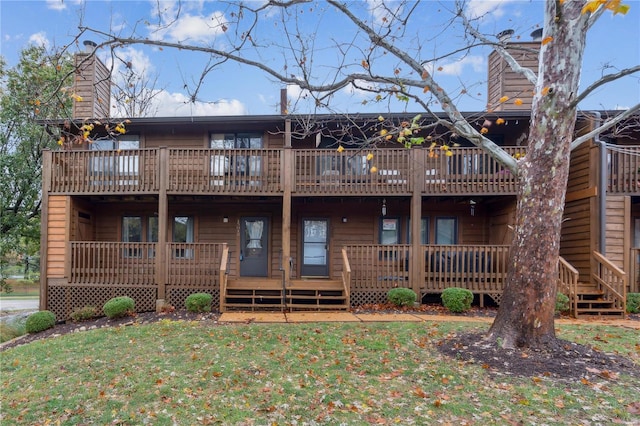 back of house featuring a lawn and a balcony