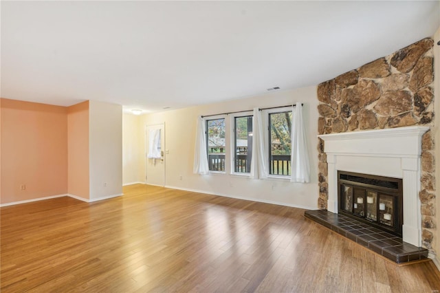 unfurnished living room featuring hardwood / wood-style flooring and a large fireplace