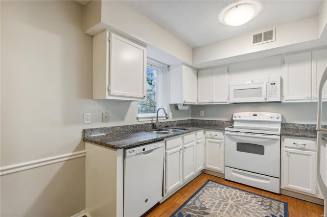 kitchen with white cabinetry, sink, a textured ceiling, white appliances, and light hardwood / wood-style flooring