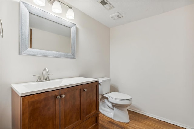 bathroom featuring wood-type flooring, vanity, toilet, and a textured ceiling