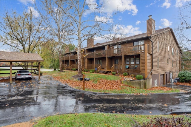 rear view of property with a balcony, a garage, a carport, and a deck