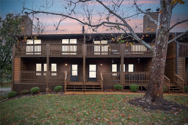 back house at dusk featuring a deck and a yard