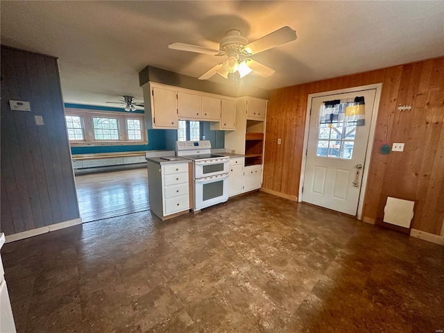 kitchen featuring white cabinetry, wood walls, ceiling fan, and range with two ovens