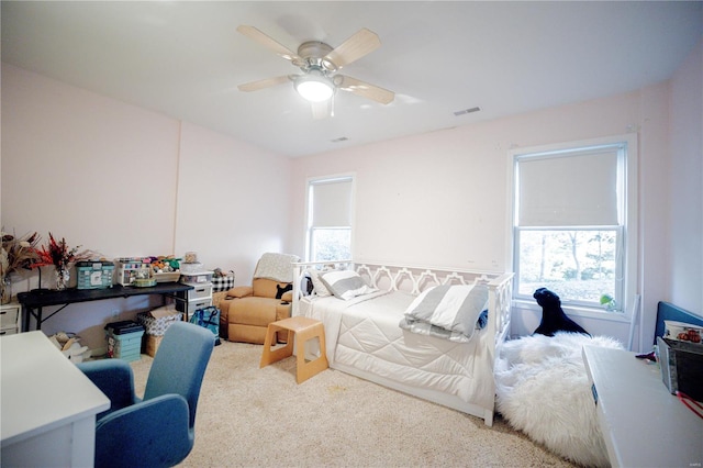 carpeted bedroom featuring multiple windows and ceiling fan