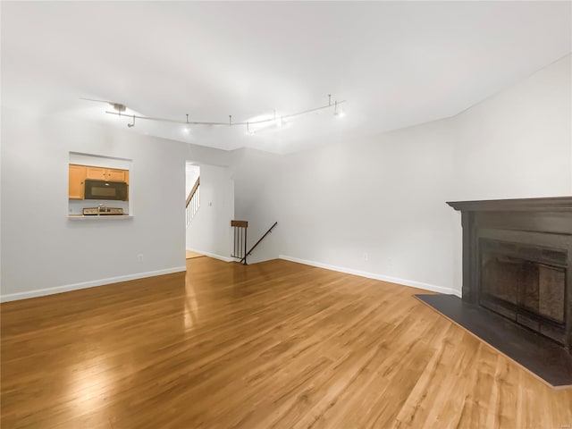 unfurnished living room with light hardwood / wood-style floors and track lighting