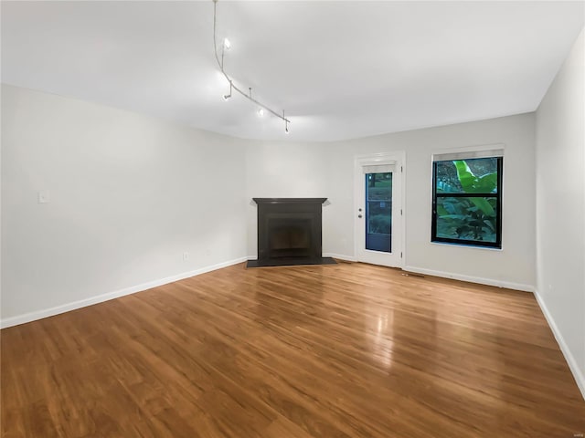 unfurnished living room featuring hardwood / wood-style floors and track lighting