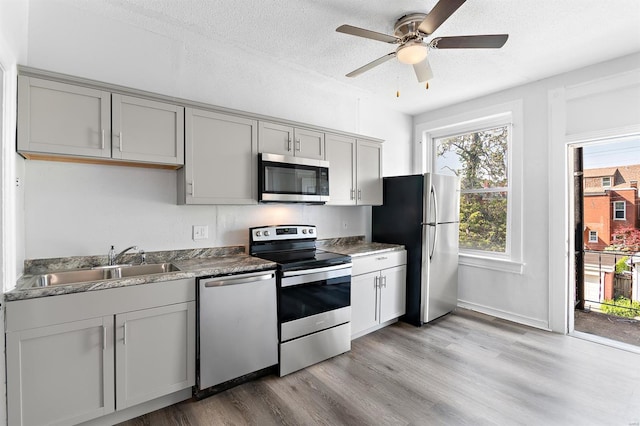 kitchen featuring a textured ceiling, stainless steel appliances, light wood-type flooring, and gray cabinetry