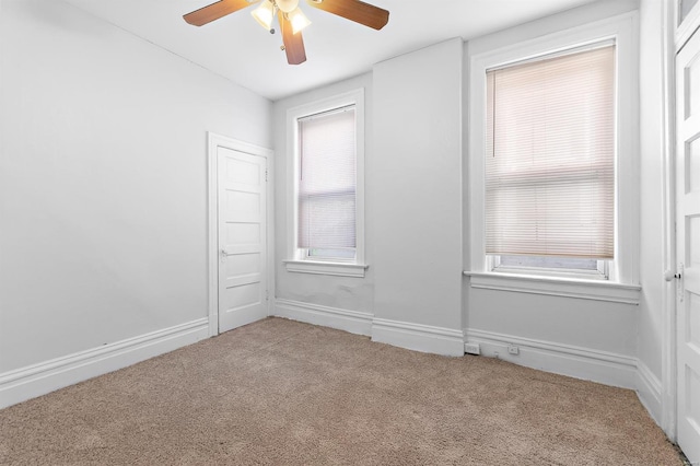 carpeted empty room with ceiling fan and plenty of natural light