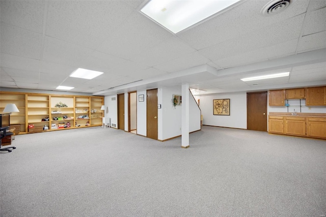 basement featuring a paneled ceiling, carpet flooring, and sink