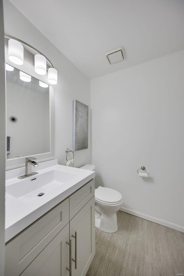 bathroom with toilet, hardwood / wood-style floors, and vanity