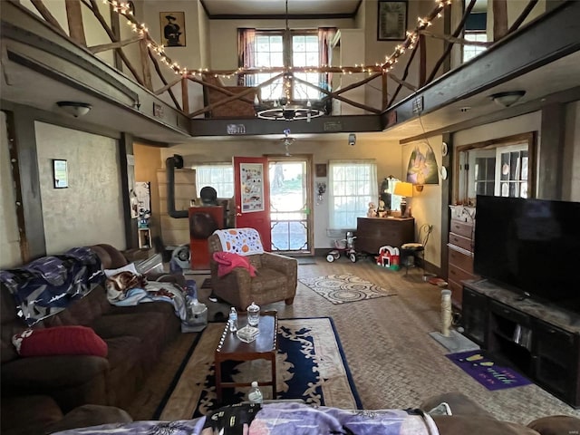 living room with a wealth of natural light, a towering ceiling, an inviting chandelier, and a wood stove