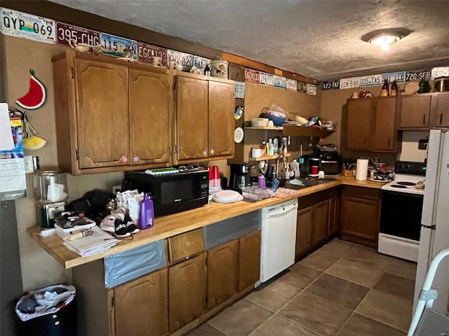 kitchen with a textured ceiling, tile patterned flooring, and white appliances