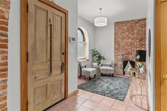 foyer featuring light tile patterned floors and a brick fireplace