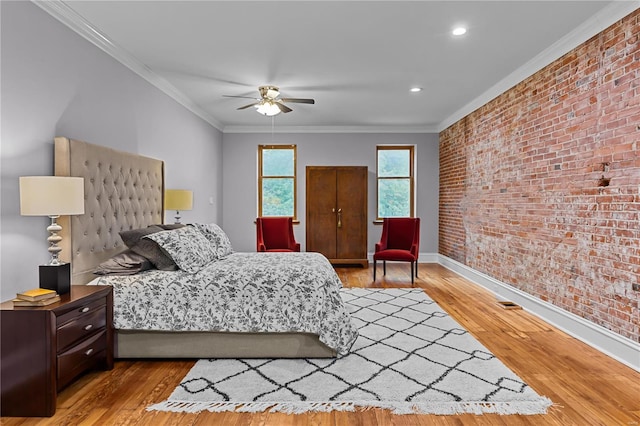 bedroom featuring ceiling fan, ornamental molding, brick wall, and hardwood / wood-style flooring