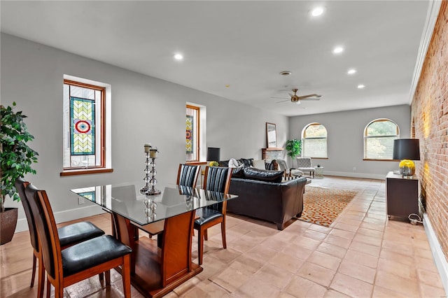 dining area featuring ceiling fan and brick wall