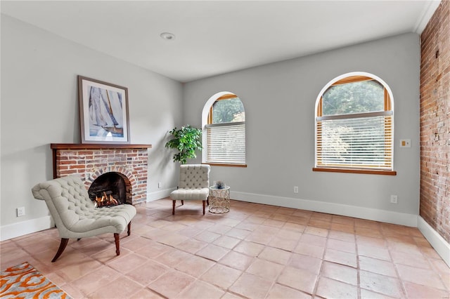 sitting room with brick wall, a brick fireplace, and light tile patterned flooring